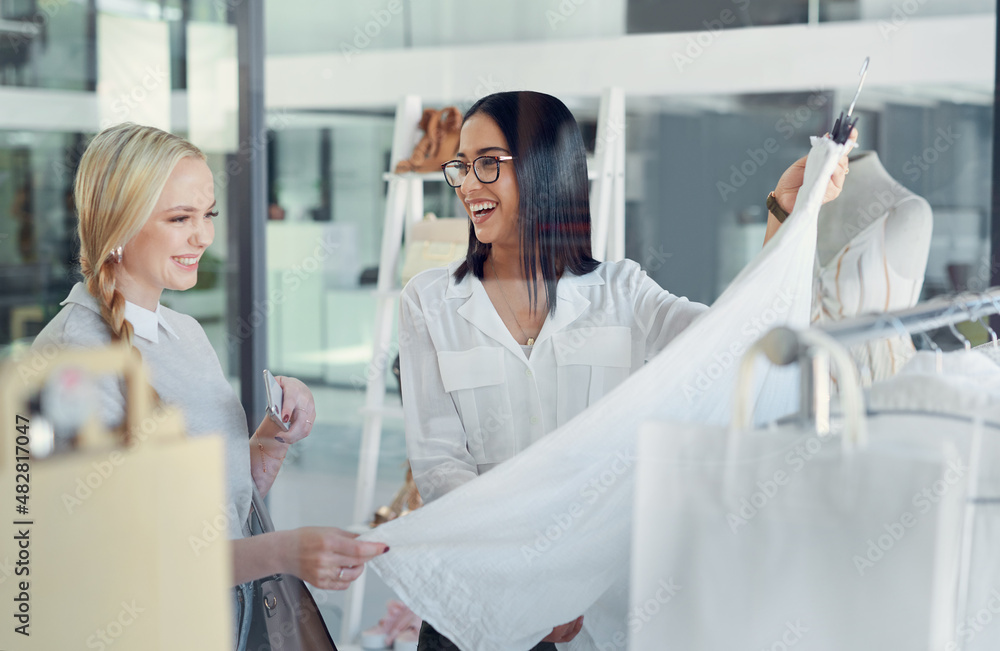 This one is my best-seller. Shot of a sales assistant helping a young woman in a clothing boutique.