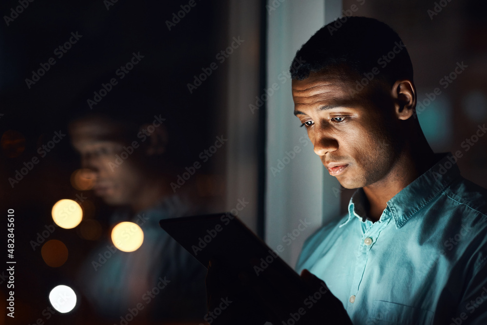 Connected throughout the whole night. Shot of a handsome young businessman using a digital tablet wh