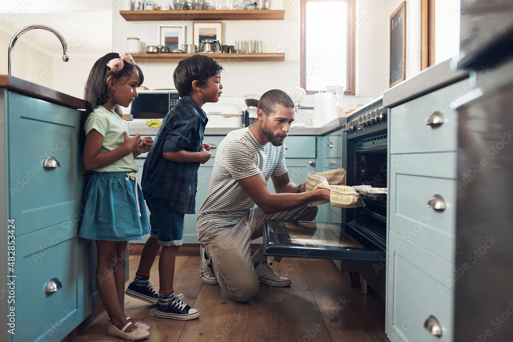 Bake the world a better place. Shot of a young man baking at home with his two young kids.