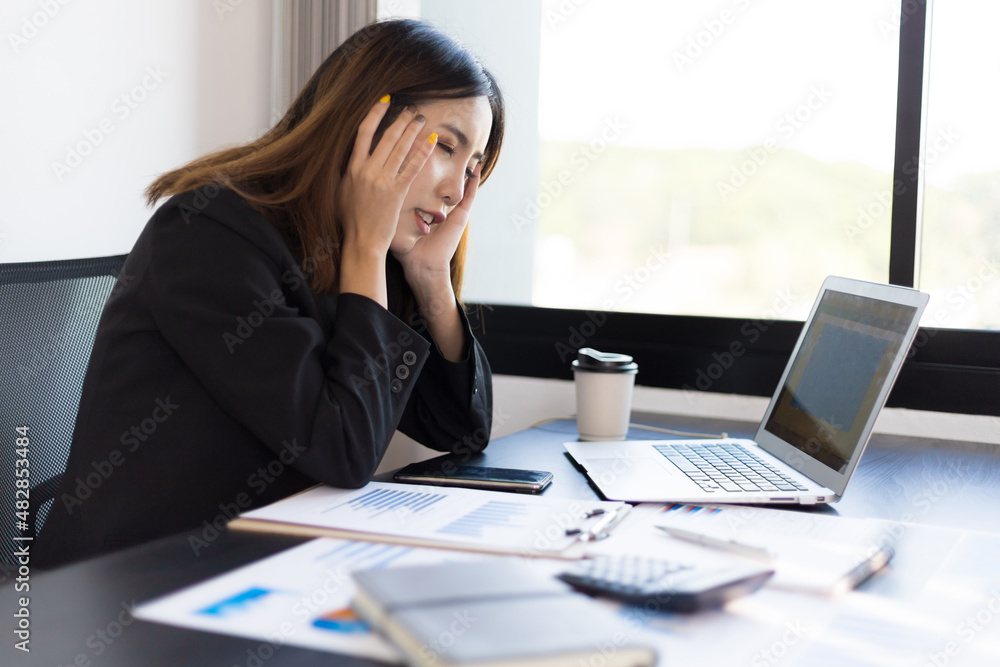 Businesswoman in the office suffering from stress headache and feeling tired and unwell.