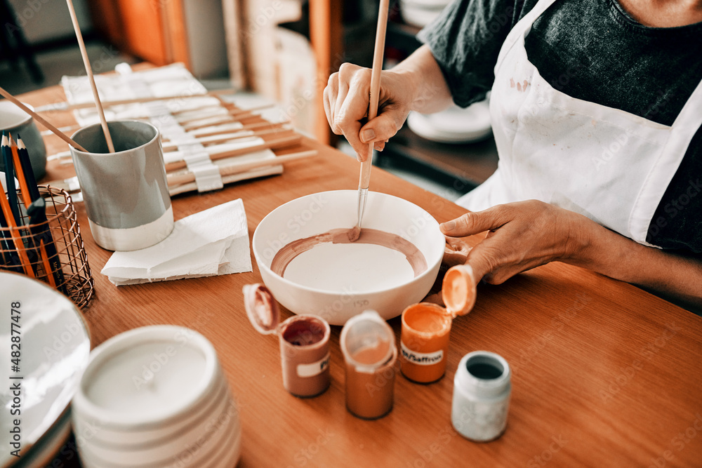 I use art to escape. Cropped shot of an unrecognizable woman sitting alone and painting a pottery bo