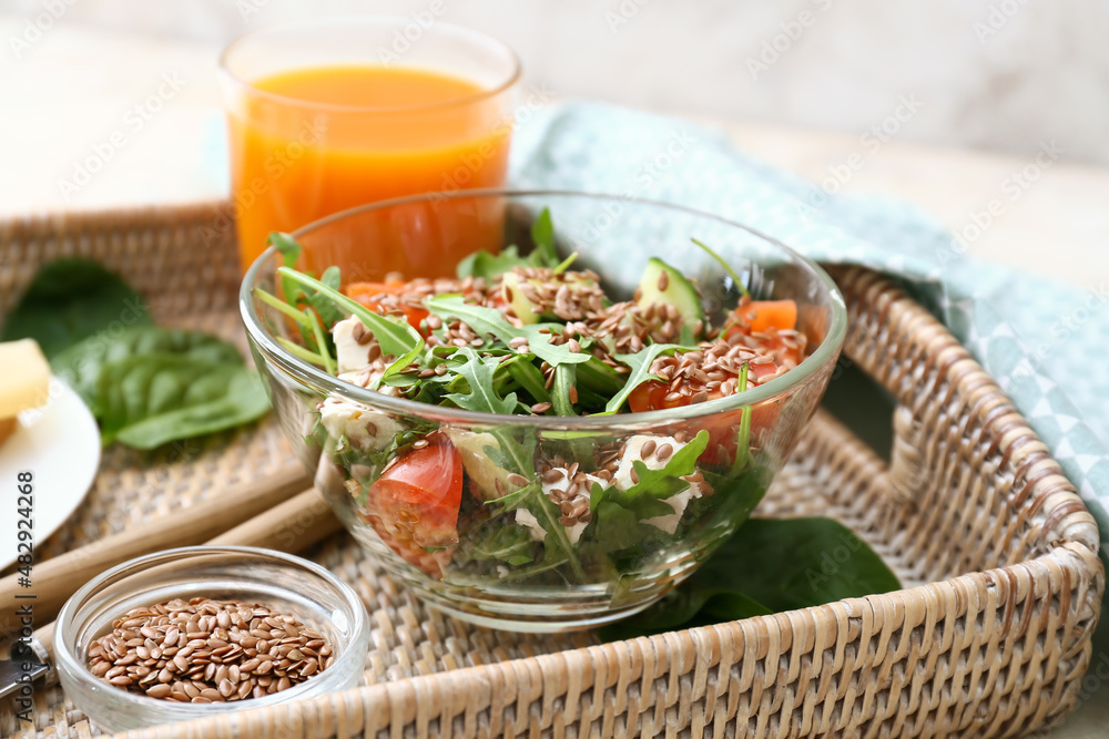 Bowl with healthy vegetable salad and flax seeds on tray