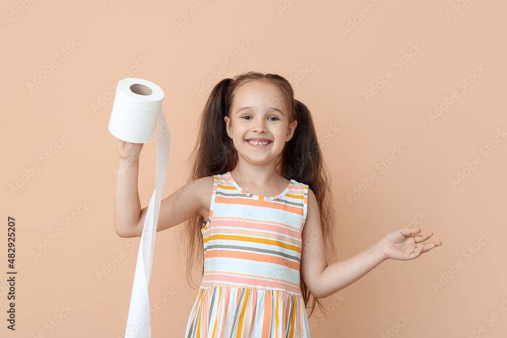 Funny little girl with ponytails holding roll of toilet paper on beige background