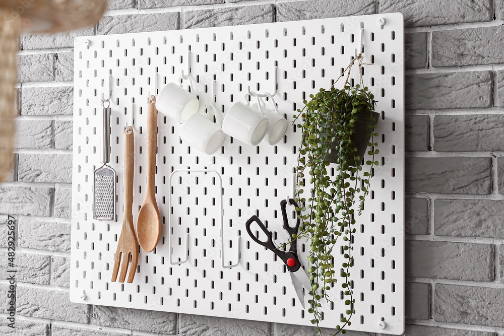 Pegboard with kitchen utensils on grey brick wall