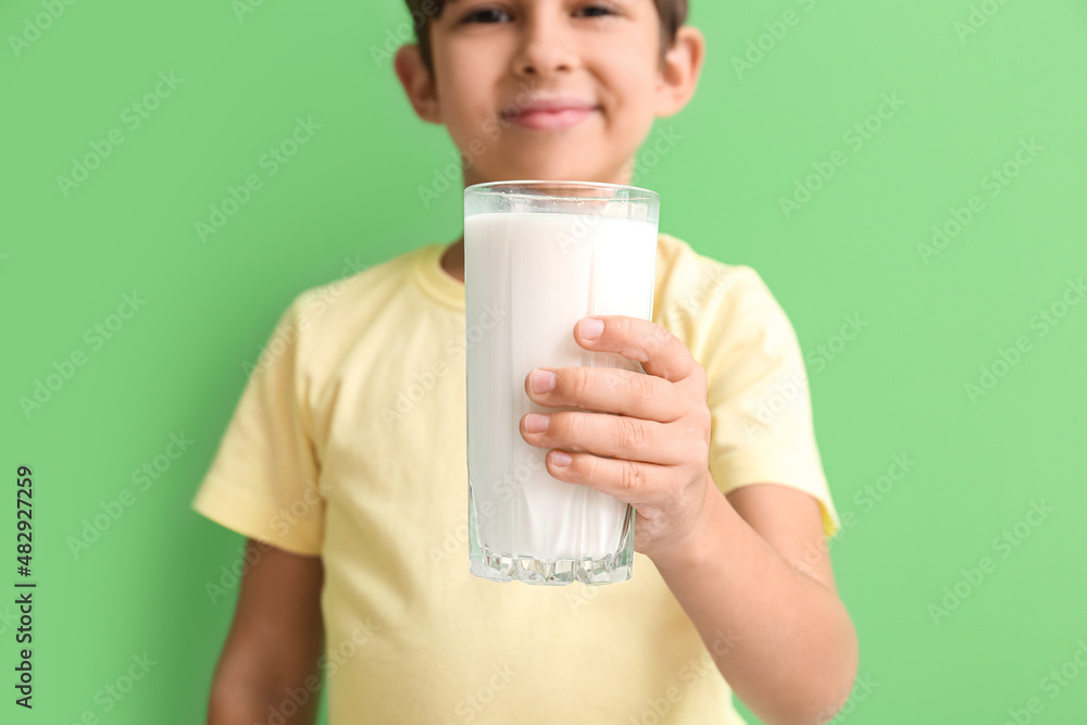 Little boy with glass of milk on green background