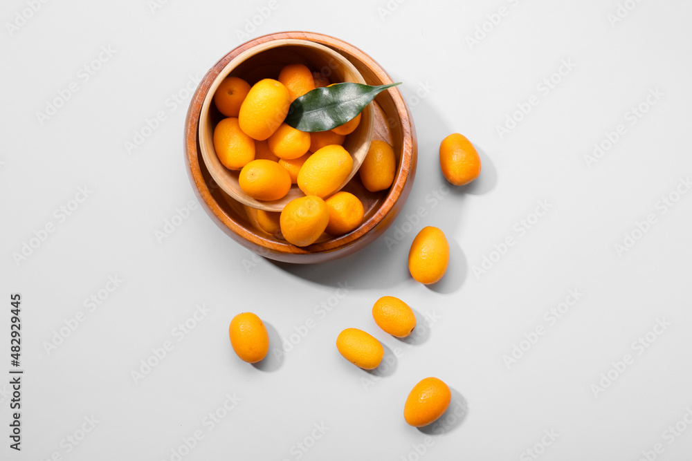 Bowl with tasty kumquat fruits on white background