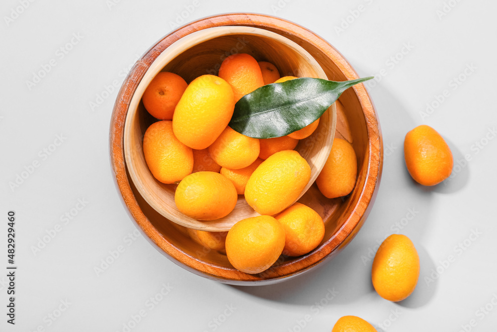 Bowl with tasty kumquat fruits on white background