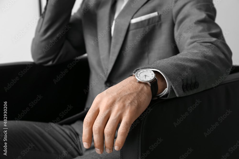 Handsome man in elegant suit and stylish wristwatch sitting in armchair, closeup