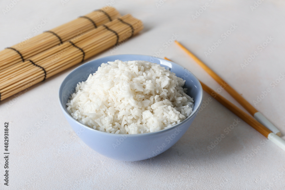 碗里有美味的煮米饭和筷子，背景浅，特写