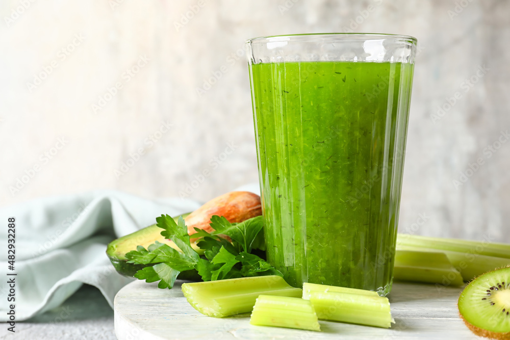 Glass of healthy green juice and fresh ingredients on light background