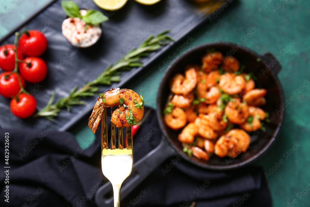 Fork with tasty shrimp tail on green background