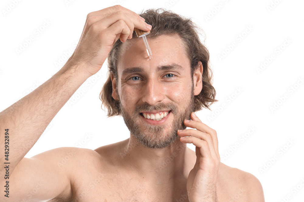 Young man using serum for skin care on white background