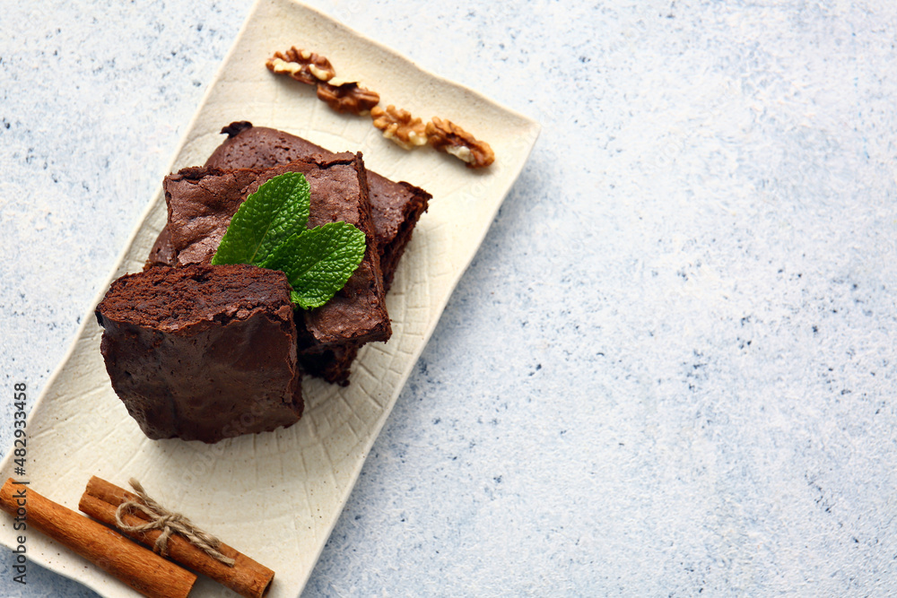 Plate with pieces of tasty chocolate brownie on white background