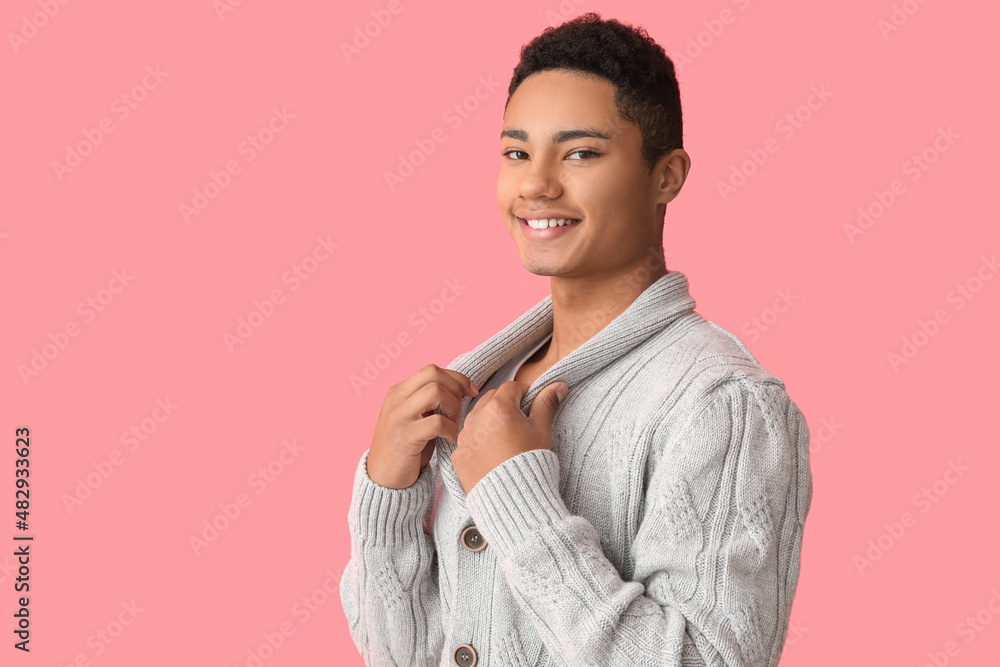 Handsome African-American guy in knitted sweater on color background