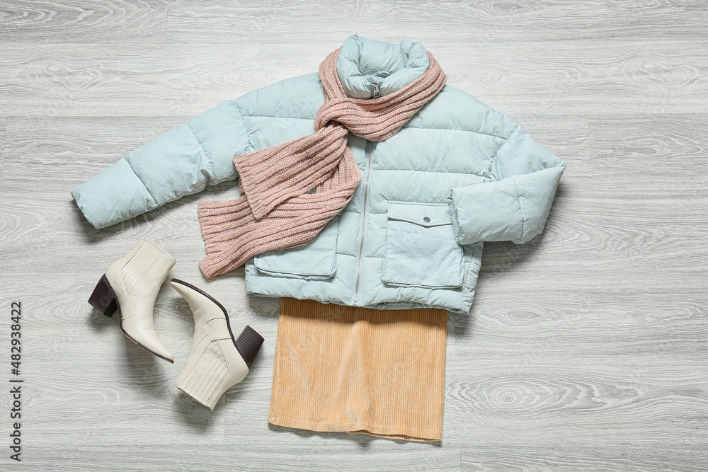 Female jacket, scarf, skirt and shoes on grey wooden background