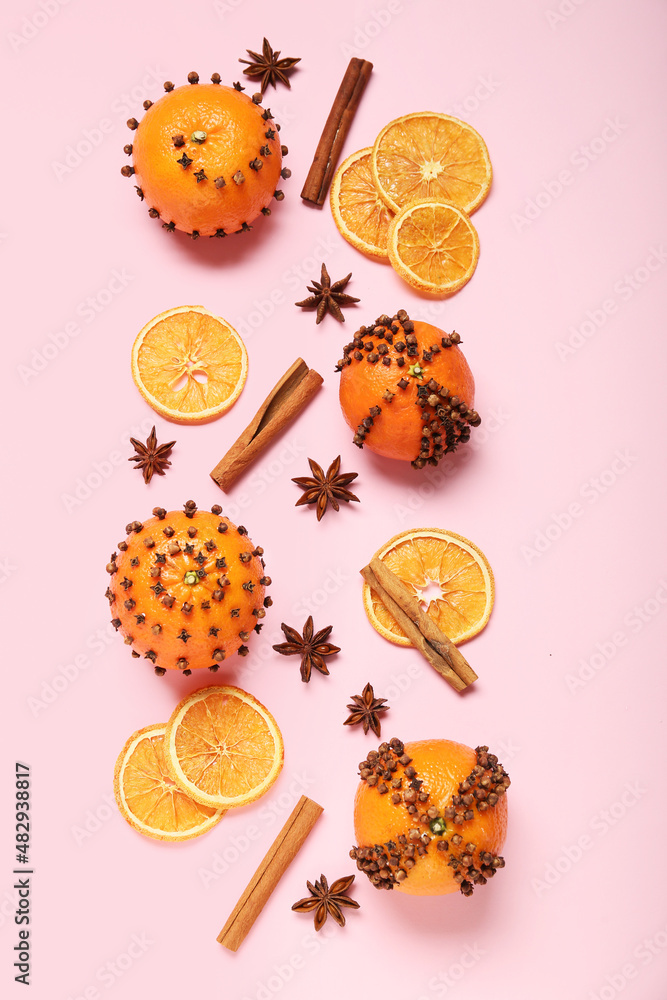 Handmade Christmas decoration made of tangerines with cloves on pink background