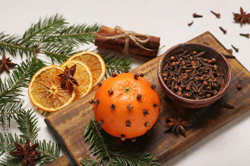 Handmade Christmas decoration made of tangerine with cloves and fir branches on light background, cl