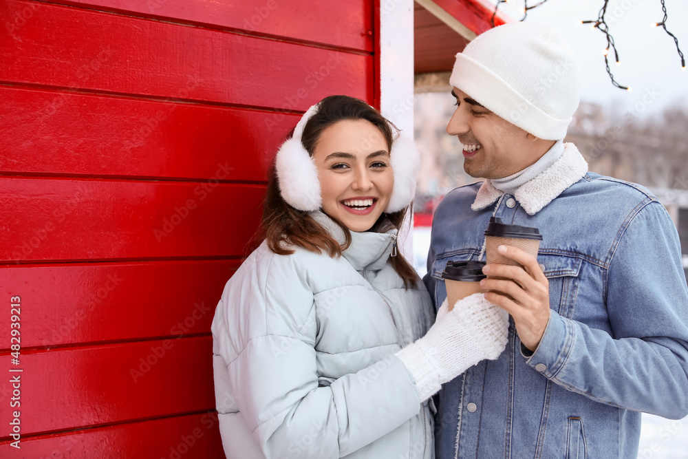 Pair of sweethearts with cups of coffee on snowy winter day