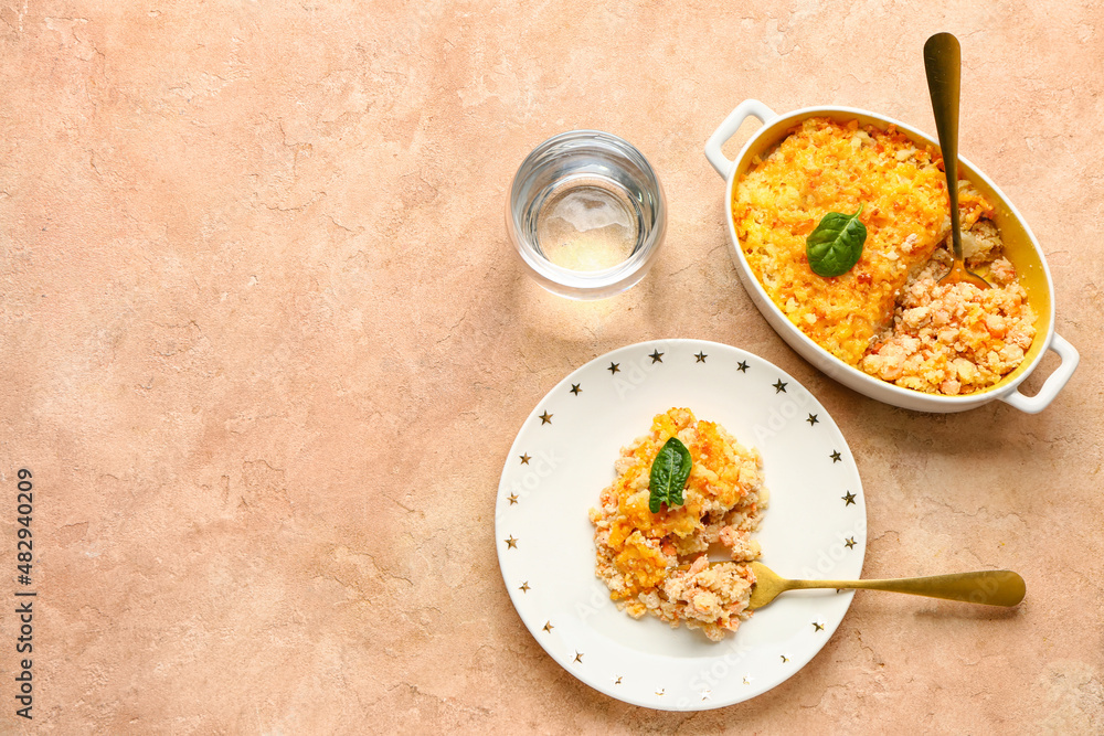 Plate and baking dish with tasty English fish pie on beige background