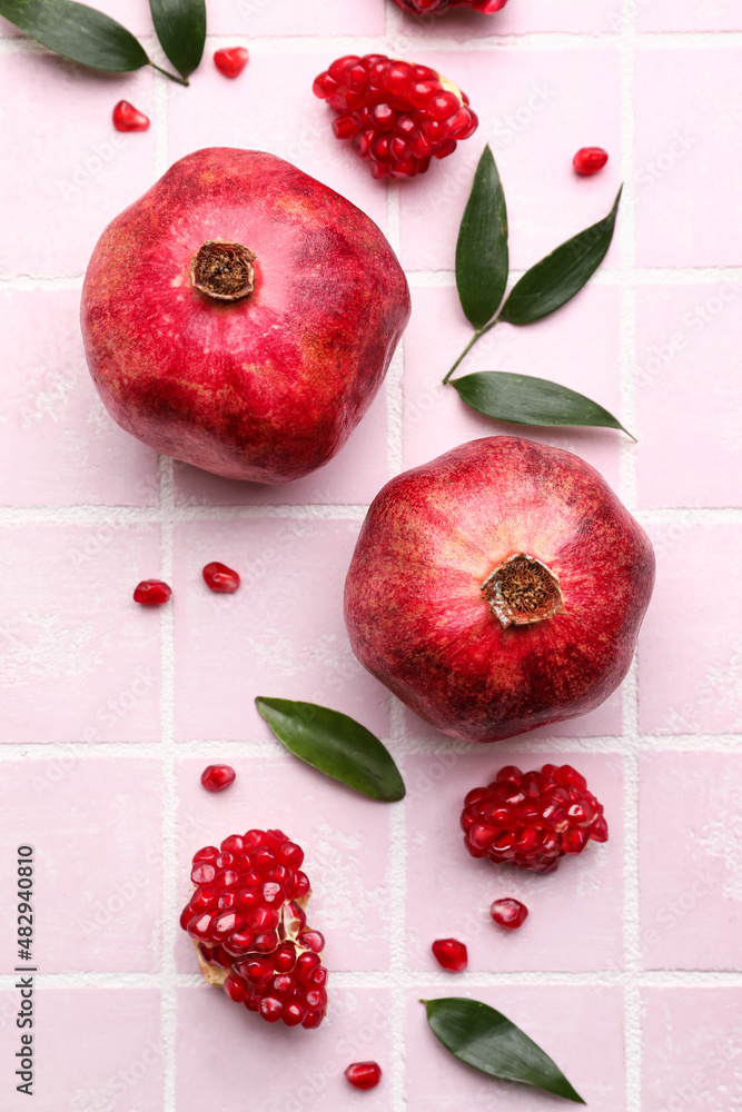 Delicious pomegranates on pink tile background