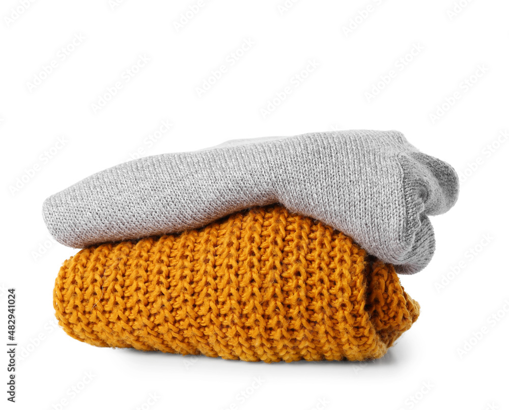 Folded knitted sweaters on white background