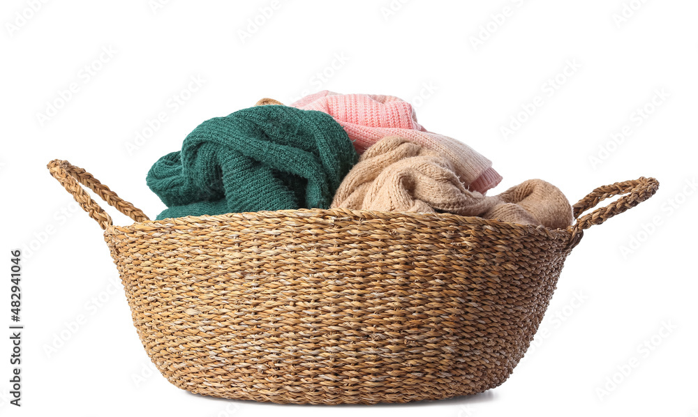 Basket with different warm sweaters on white background