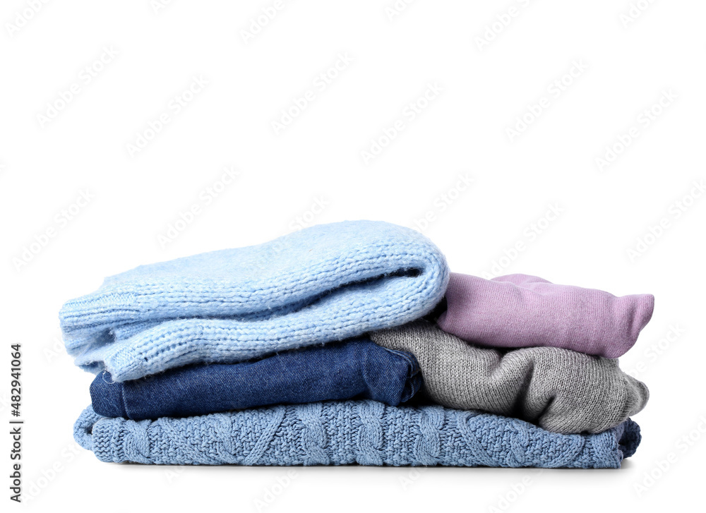 Stack of different soft sweaters on white background