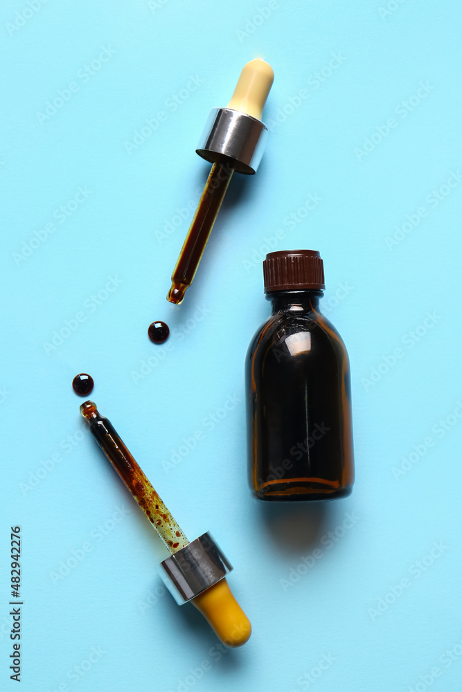 Bottle with iodine and pipettes on blue background