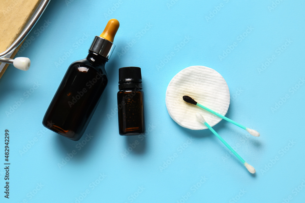 Bottles with iodine, cotton swab and pad on blue background