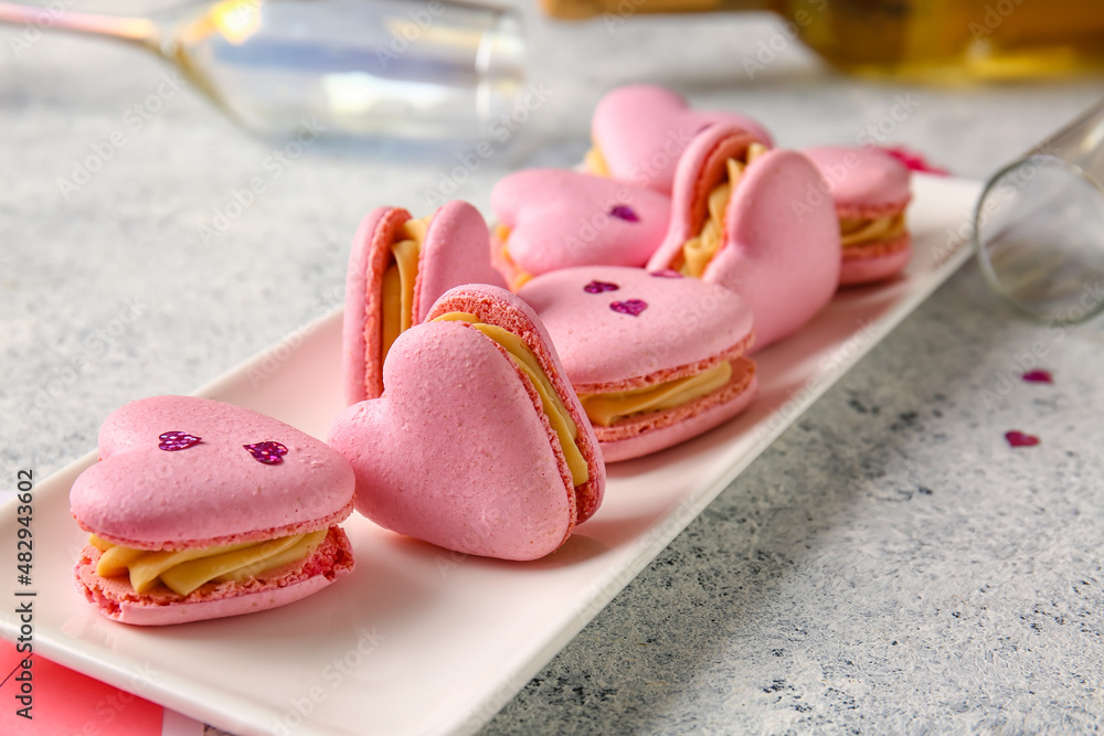 Plate with tasty heart-shaped macaroons on light background, closeup