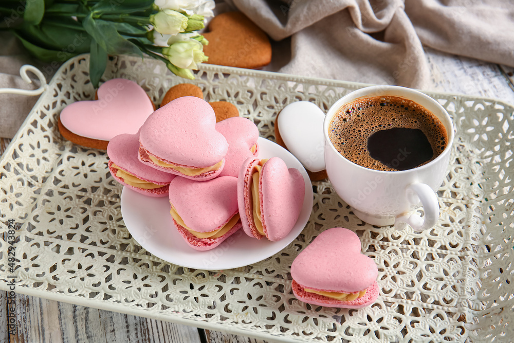 Tray with tasty heart-shaped macaroons and cup of coffee on table