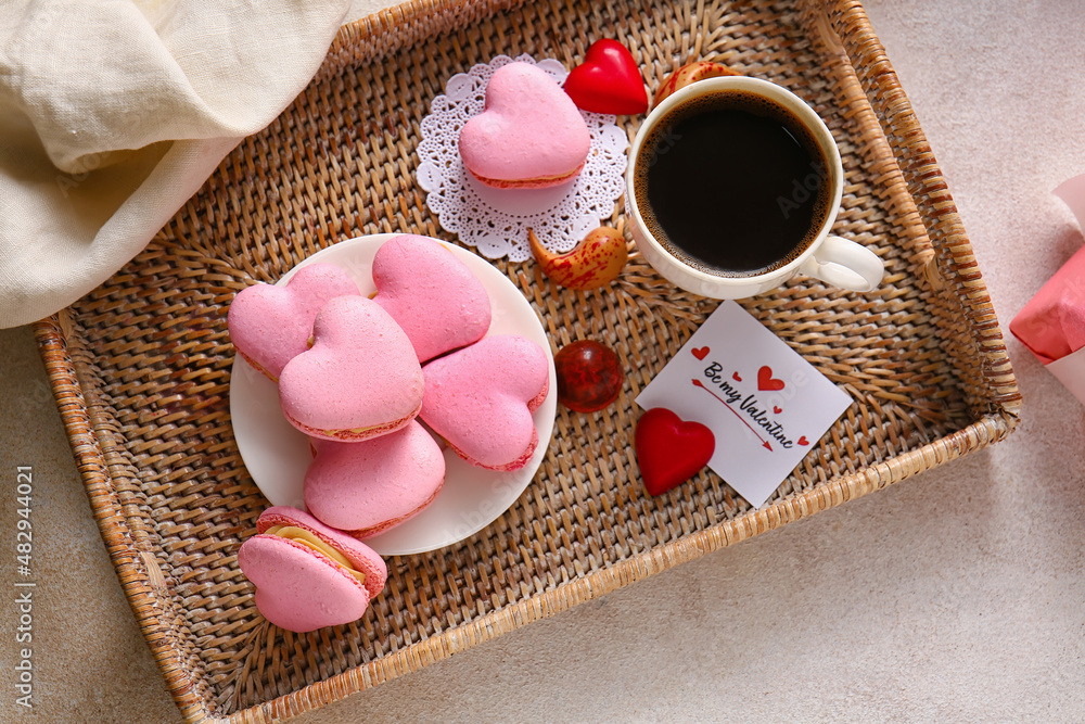 Tray with tasty heart-shaped macaroons and cup of coffee on light background