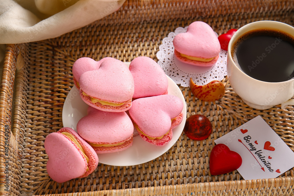 Tray with tasty heart-shaped macaroons and cup of coffee on table