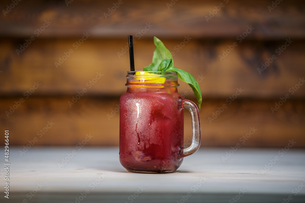 Fresh pomegranate lemonade with crushed ice and mint and straw on table with wood background