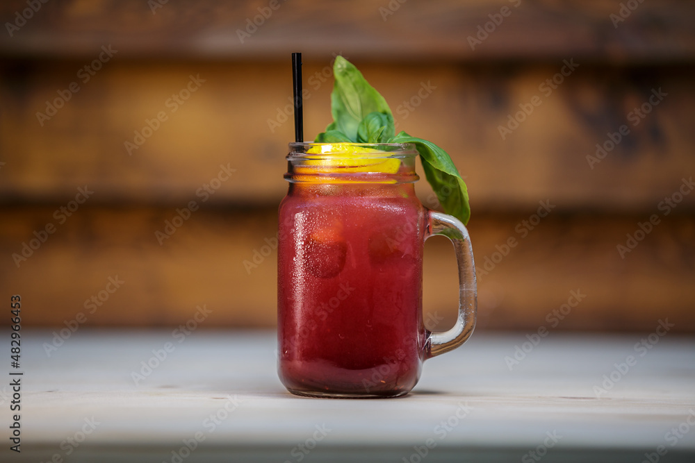 Fresh pomegranate lemonade with crushed ice and mint and straw on table with wood background