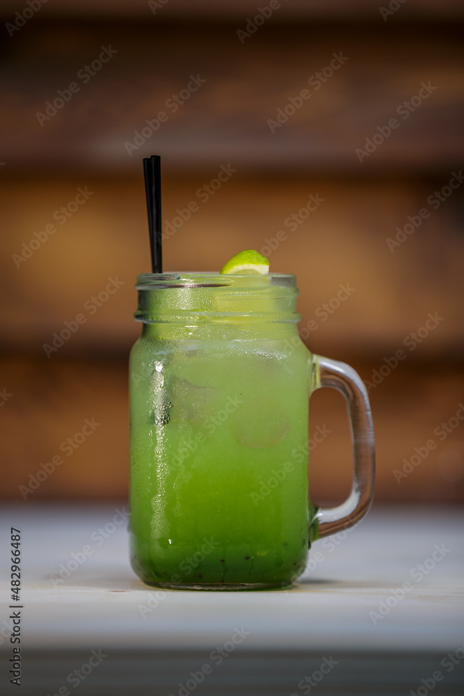 Fresh kiwi lemonade with crushed ice and lime and straw on table with wood background