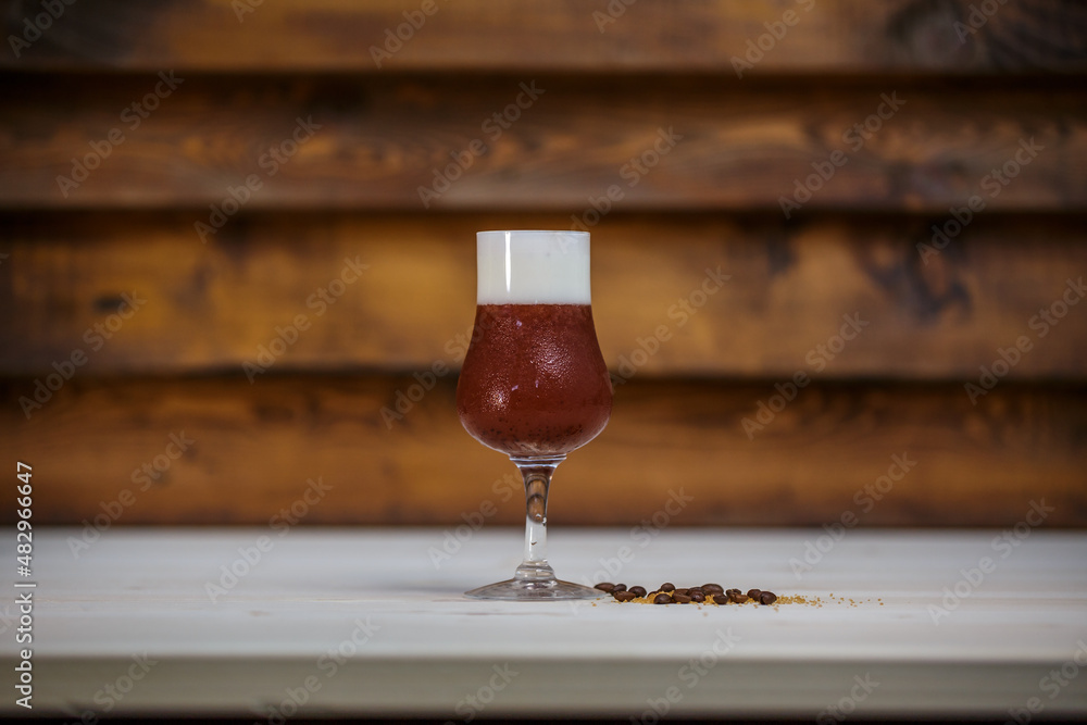 Crushed ice coffee with cinamon in brandy glass on table with wood background and coffee beans