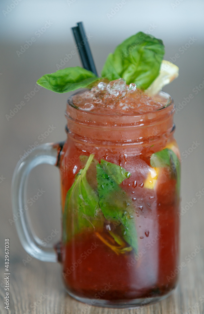 Fresh pomegranate lemonade detail with crushed ice and mint and straw on table with wood background