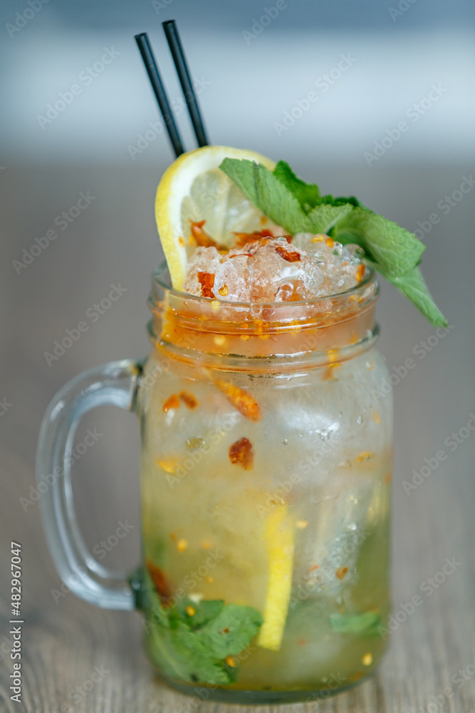 Fresh passion fruit detail with crushed ice and lemon and straw on table with blueish background