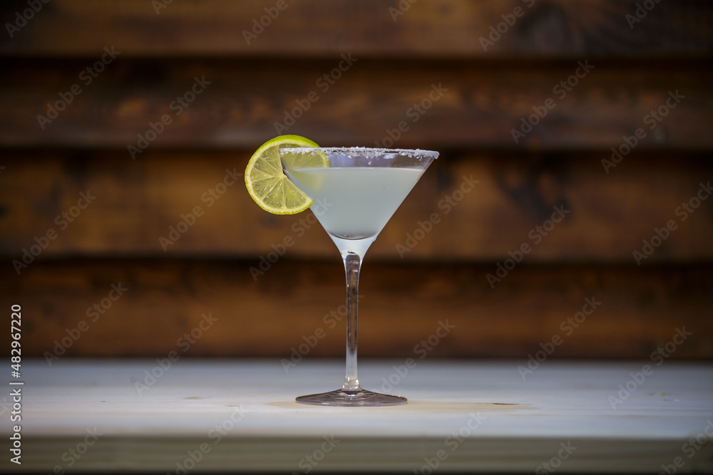 Fresh cold martini cocktail glazed and crushed ice with lime garnish on table with wood background