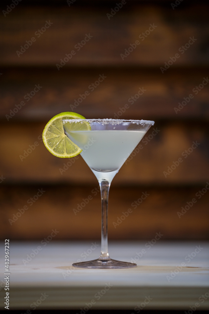 Fresh cold martini cocktail glazed and crushed ice with lime garnish on table with wood background