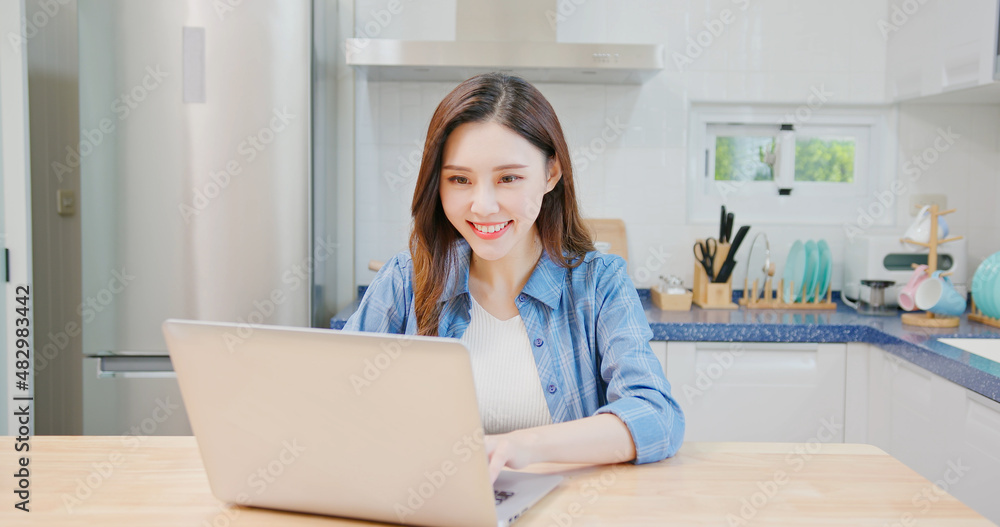 woman uses laptop at kitchen