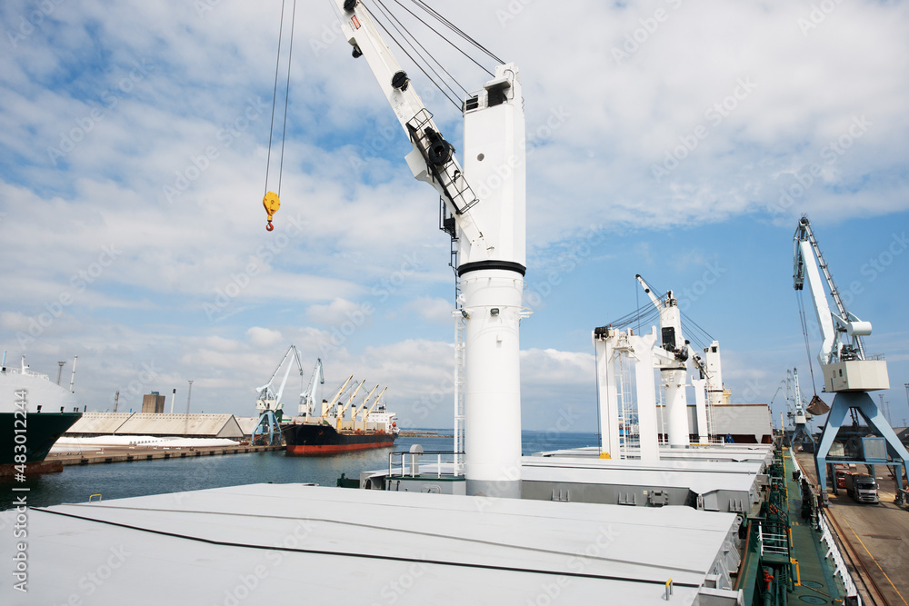 The shipyard never sleeps. A photo of a harbor with anchored ships with cranes.