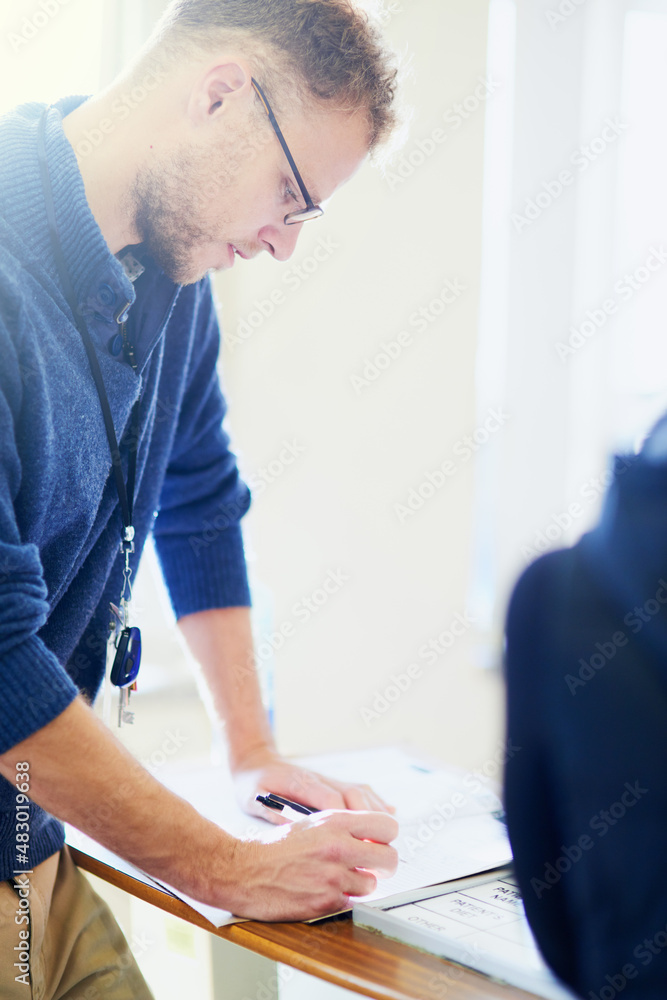 Taking care of those pre-admission papers. Shot of a young doctor filling out paperwork in a hospita