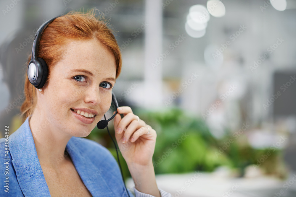 Assistance is a phone call away. Shot of an attractive red headed female wearing head sets in an off