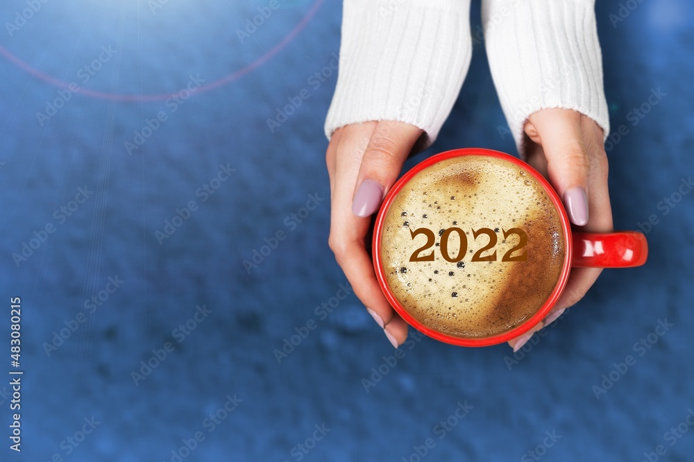 女性手拿杯子喝卡布奇诺表面的数字2022