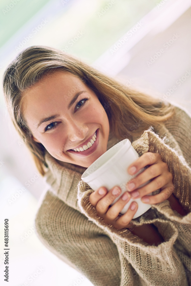 Enjoying a cup of positivi-tea. Portrait of a young woman enjoying a warm beverage at home.