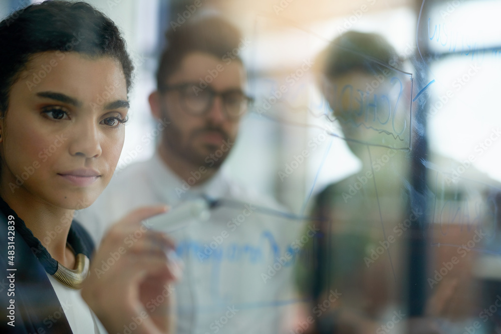 Succeeding is top priority. Shot of a group of colleagues brainstorming together on a glass wall in 