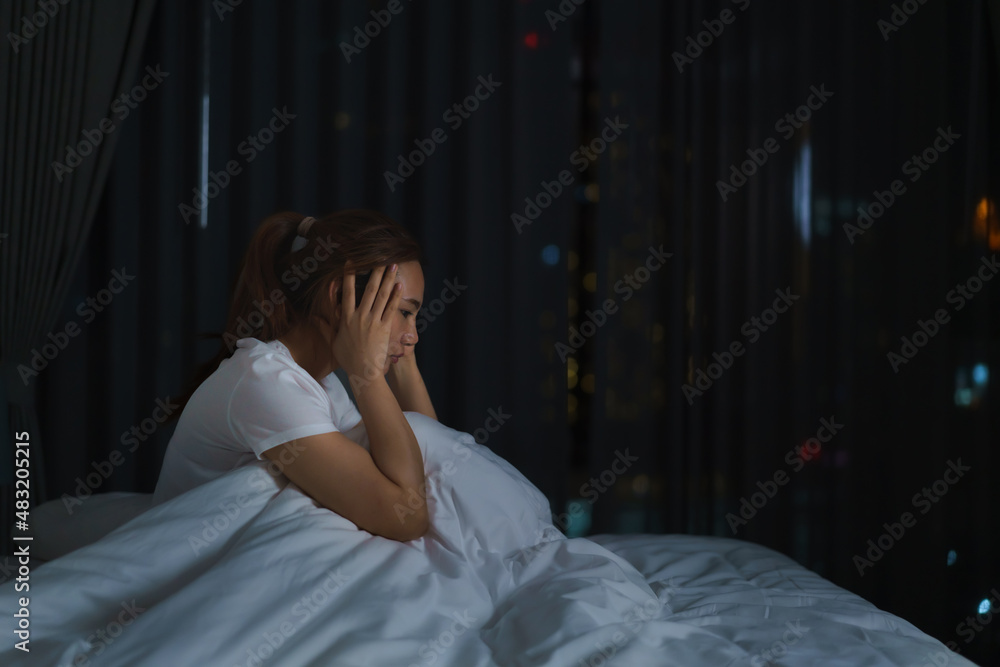 Asian woman lying on a white bed in the bedroom looking worried or thinking about something about he