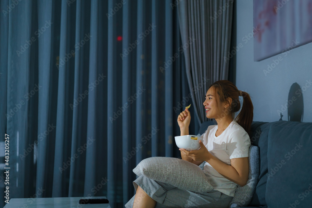 asian woman watching television suspense movie or news looking happy and funny and eating popcorn la